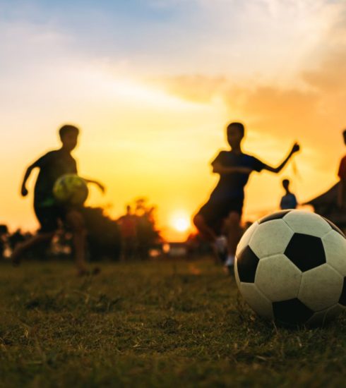 Deti hrajú futbal pri západe slnka